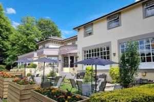 a house with chairs and umbrellas in front of it at Reigate Manor Hotel in Reigate