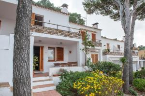 une maison blanche avec des arbres et des fleurs dans l'établissement Sa Tuna "Casas CE MA", à Begur