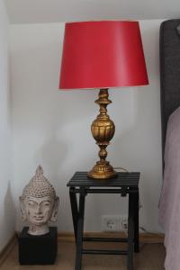 a red lamp on a table next to a bed at Bed & Breakfast Bodensee mit Herz in Stockach +25 photos