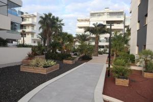 a walkway in a courtyard with palm trees and buildings at Greenhills La Zenia luxe penthouse 5 pers Orihuela in Los Dolses