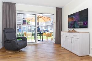 a living room with a chair and a sliding glass door at Ferienwohnungen Min Huus in Neuharlingersiel