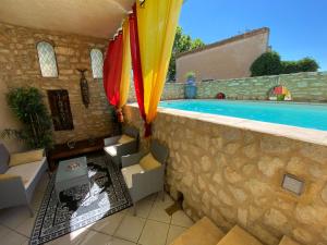 un patio con piscina y una pared con sombrillas en Hotel Le Saint Laurent en Saint-Laurent-des-Arbres