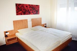Ce lit se trouve dans une chambre ornée d'une peinture rouge sur le mur. dans l'établissement Hotel Meuser, à Wiesbaden