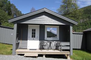 una casita negra con sillas en un porche en Tvinde Camping, en Skulestadmo