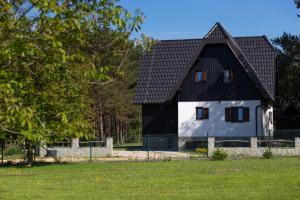 a black and white house with a fence at Timber valley in Plitvička Jezera