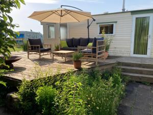 - une terrasse avec 2 chaises et un parasol dans l'établissement Classic bungalow by the IJsselmeer, à Workum