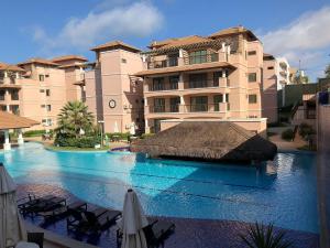 a swimming pool in front of a large building at Apartamento Beverly Hills - Próximo ao Beach Park in Aquiraz