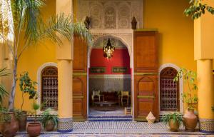 une entrée dans un bâtiment aux murs jaunes et aux palmiers dans l'établissement Medina social club, à Fès