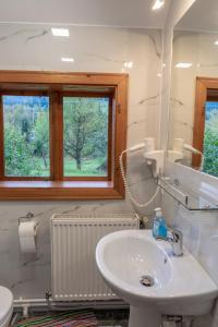 a white bathroom with a sink and a window at Pensiunea Poiana de Vis in Suceviţa
