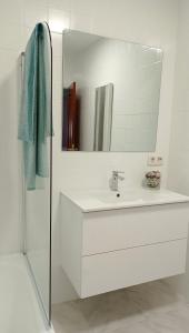 a white bathroom with a sink and a mirror at O Lagar apartamento grande y luminoso. 8 personas. in Pobra do Caramiñal