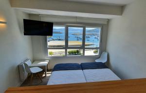 a bedroom with a bed and a large window at Apartamentos Costa da Morte Muxia in Muxia