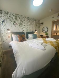 1 cama blanca grande en un dormitorio con papel pintado con motivos florales en The Hive at Poppi-Red en Hawkshead