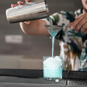 a person is pouring blue liquid into a glass at Hotel Rema in Vourvourou