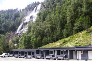 un edificio con panchine di fronte a una cascata di Tvinde Camping a Skulestadmo
