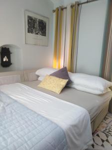 ein großes weißes Bett mit gelbem Kissen darauf in der Unterkunft Quacketta in Villajoyosa