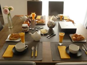 a table with a breakfast of croissants and orange juice at Chambres d'hôtes dans maison contemporaine in Vernouillet