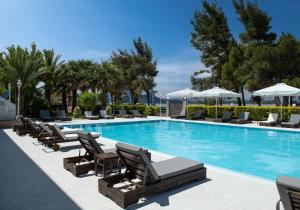 a swimming pool with lounge chairs and umbrellas at Hotel Rema in Vourvourou