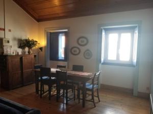 ein Esszimmer mit einem Tisch und Stühlen sowie 2 Fenstern in der Unterkunft Azoia 10 - Casas de Campo & Hostel in Azoia de Baixo