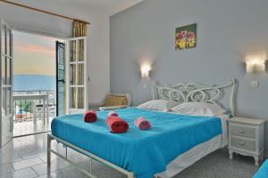 a bedroom with a blue bed with red towels on it at Fotini Studios in Paleokastritsa