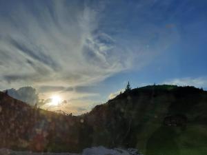 a sunset over a hill with the sun setting on the horizon at Agritur Bolser in San Vigilio Di Marebbe