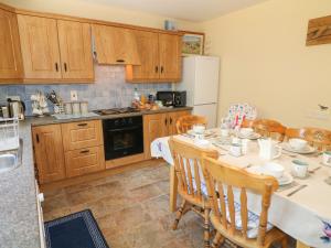 cocina con mesa, sillas y nevera en Slieve Gallion Cottage, en Magherafelt