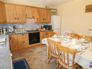 a kitchen with a table and chairs and a refrigerator at Slieve Gallion Cottage in Magherafelt
