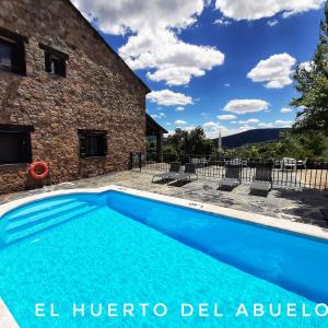 uma piscina em frente a uma casa de pedra em Casa Rural y Spa El Huerto del Abuelo em Almiruete
