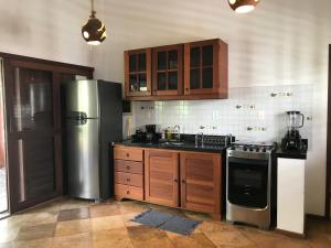 La cuisine est équipée d'armoires en bois et d'un réfrigérateur en acier inoxydable. dans l'établissement Casa Bouganville apartamento 4, à Jericoacoara