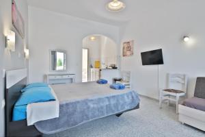 a white bedroom with a bed and a chair at Fotini Studios in Paleokastritsa