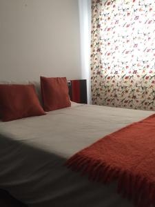 1 dormitorio con cama con almohadas rojas y cortina en Atico Vilagarcia, en Vilagarcía de Arousa