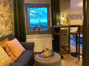 a living room with a couch and a table and a window at dashausderfloristin in Noertrange