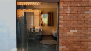 a room with a brick wall and a glass doorway at Chalés Vila Bela Vale do Capão in Vale do Capao