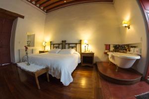 a bedroom with a bed and a tub and a sink at Hotel Boutique Posada La Basilica in Pátzcuaro
