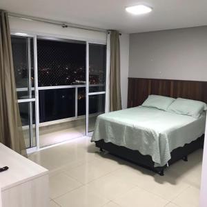 a bedroom with a bed and a large window at Flat The Expression 1210 in Goiânia