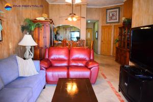 a living room with a red leather couch and a table at Marina Pinacate B-102 in Puerto Peñasco
