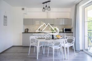 una cucina con tavolo e sedie bianchi di Apartament Grey a Szklarska Poręba
