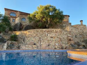 a large swimming pool in front of a stone building at Hotel Monasterio de Rocamador in Almendral