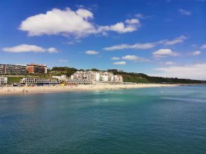 a beach with buildings and people in the water at Poseidon Friends in Bournemouth