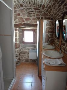 een badkamer met 2 wastafels en een stenen muur bij Plein pied dans maison de caractère in Montjaux