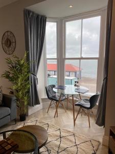 a living room with a table and a view of the ocean at Belmont Apartment 2 in Aberystwyth