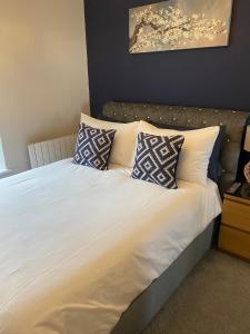 a bed with white sheets and pillows in a bedroom at Belmont Apartment 2 in Aberystwyth