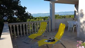 two yellow chairs and a table on a balcony at Apartmani Diva in Malinska