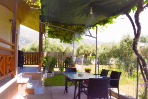 a patio with a table and chairs under a canopy at Kapsogeorgis Rooms in Koinyra
