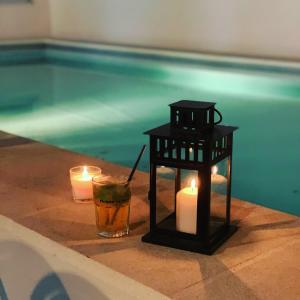 a table with candles and a drink next to a swimming pool at UNE HISTOIRE DE FAMILLE in Collobrières