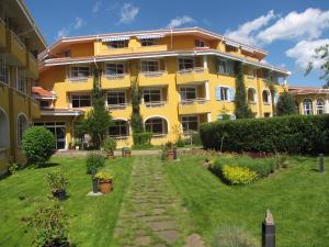 a yellow building with a garden in front of it at Blue Orange Beach Resort in Sozopol