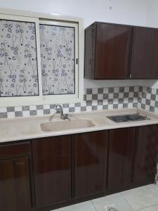 eine Küche mit einem Waschbecken und zwei Fenstern in der Unterkunft ريـــــم للشقق المفروشة والأجنحــة الفـندقيـة Reem Hotel in Khobar