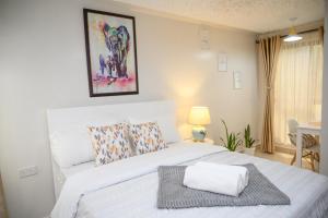una camera da letto con un letto bianco e un asciugamano sopra di Furnished 1 Bedroom Apartment in Nairobi. 15 Mins to CBD. Free WI-FI & Parking a Nairobi