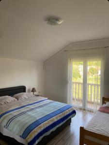 a white bedroom with a bed and a window at Apartmani Svitavac in Trebinje