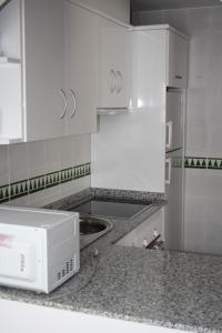 a white kitchen with a microwave on a counter at Apartamentos Torrelaguna in Vera
