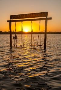 a swing in the water with the sunset in the background at Pousada Flambaião in Jijoca de Jericoacoara